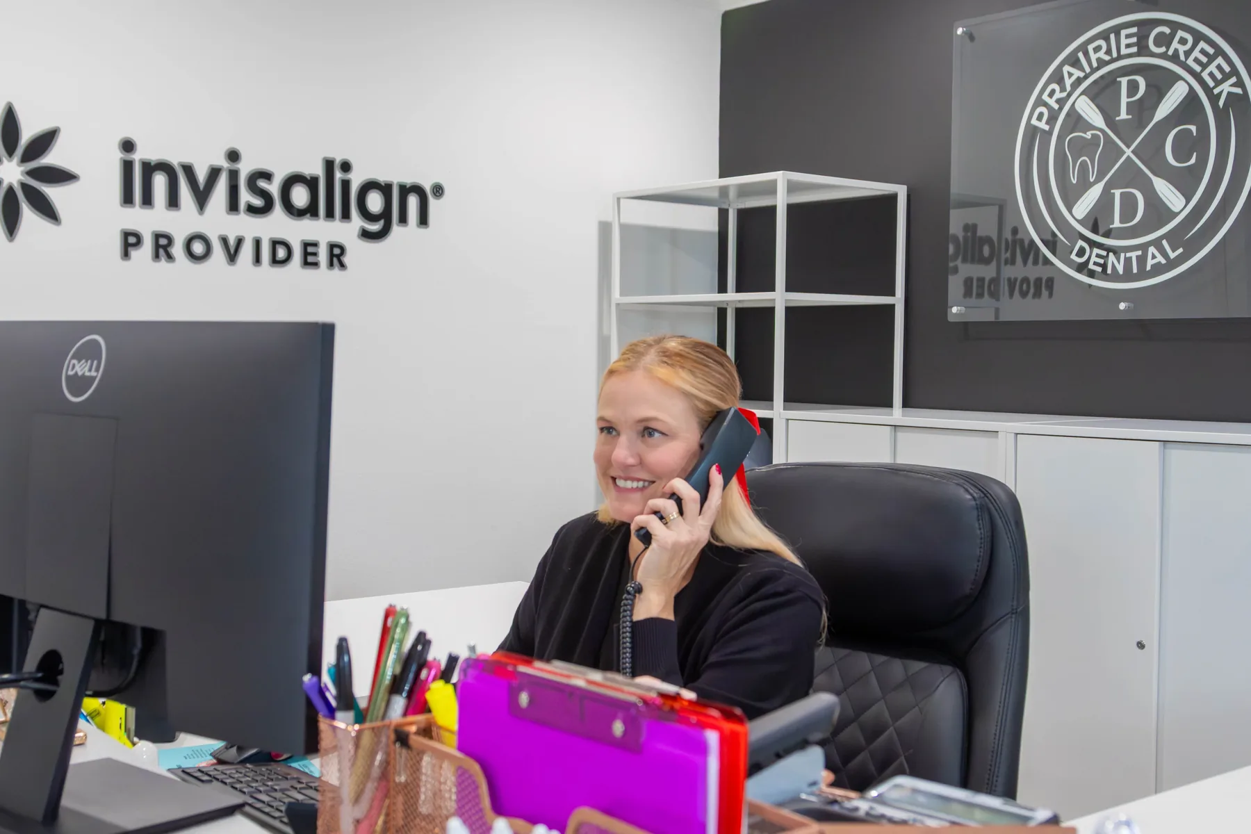 Prairie Creek Dental team member smiling while answering the phone at the front desk