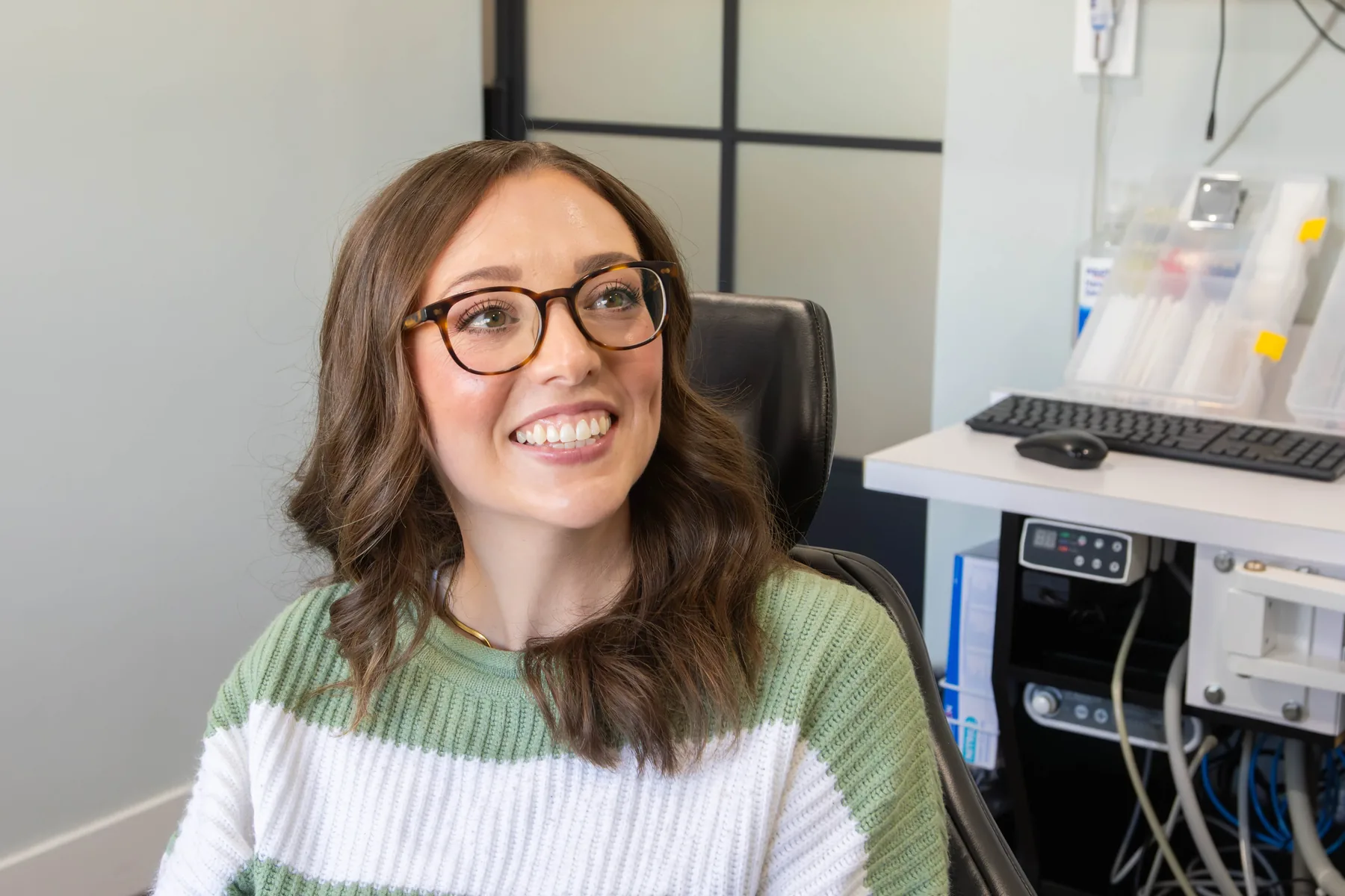 Smiling patient with glasses sitting in a treatment chair at Prairie Creek Dental