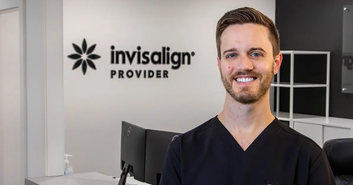 Happy couple outdoors in autumn with bare trees and warm sunlight, woman hugging man from behind smiling