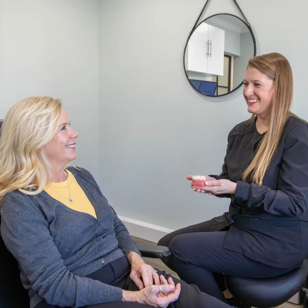 Smiling middle-aged Asian man with gray hair and beard wearing a blue shirt outdoors with blurred background.