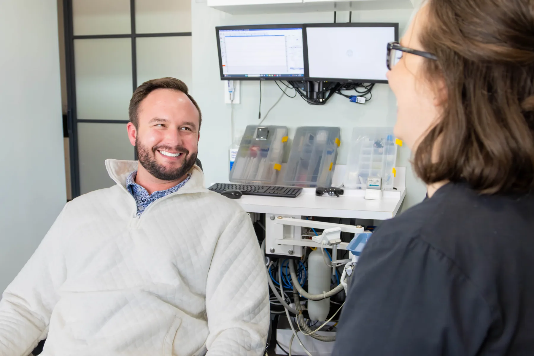Smiling patient in a white pullover chatting with a team member in a Prairie Creek Dental treatment room
