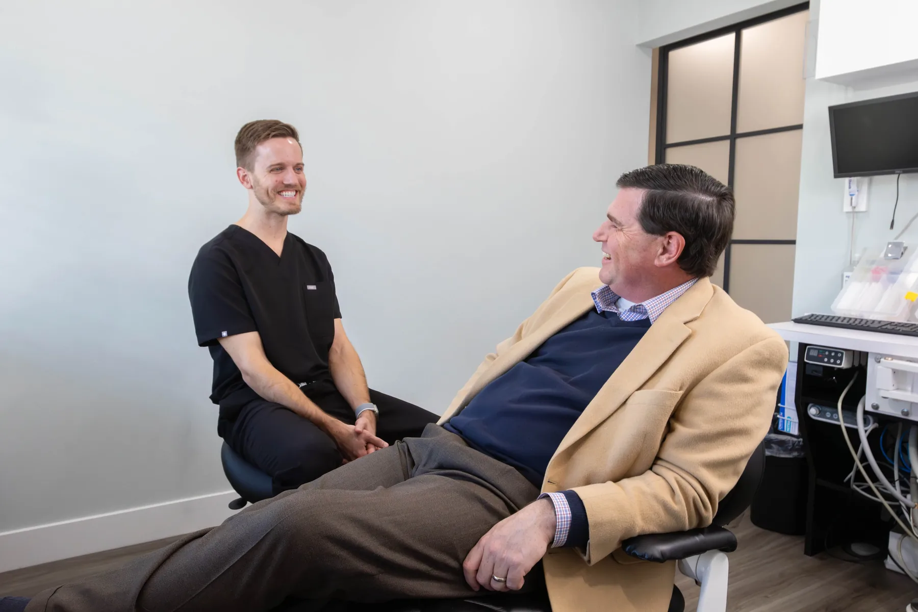 Dental team member in black scrubs laughing with a patient in a treatment room at Prairie Creek Dental
