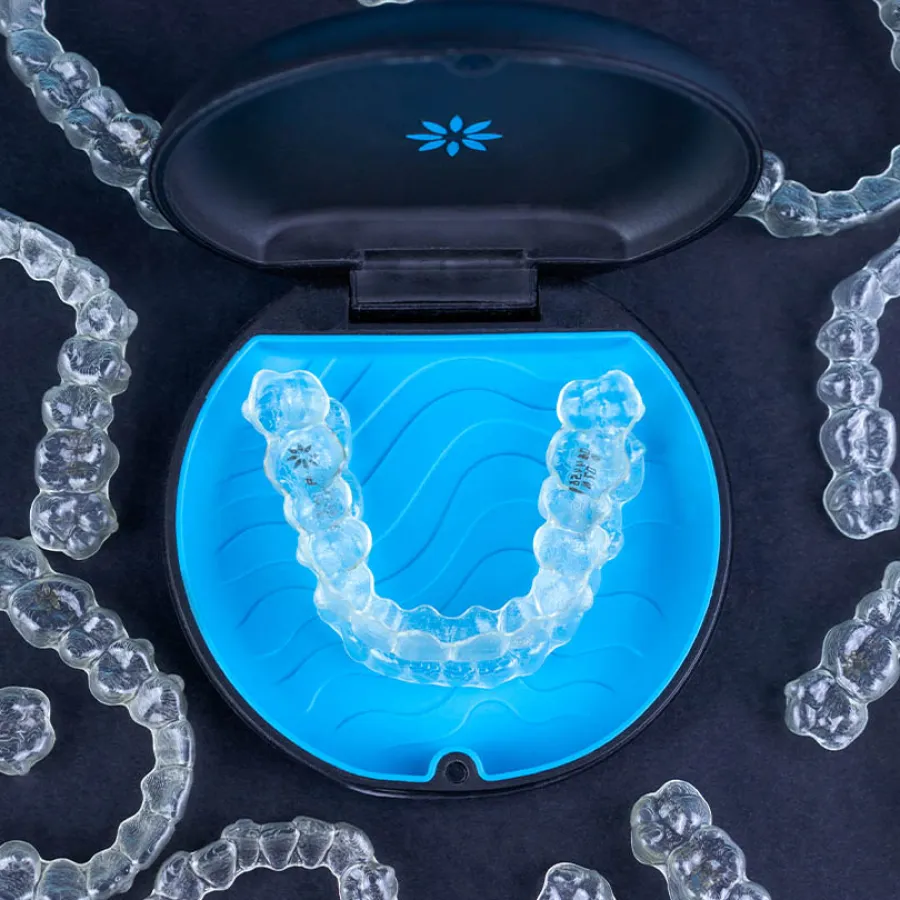 Clear Invisalign aligner against a blue background with Invisalign provider logo visible.