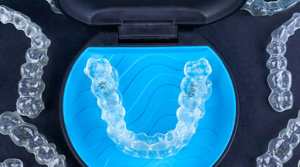 Clear Invisalign aligner against a blue background with Invisalign provider logo visible.