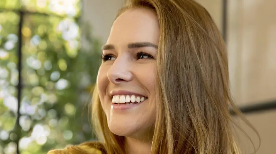 Clear Invisalign aligner against a blue background with Invisalign provider logo visible.